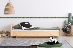 a panda bear laying on top of a bed in a room with green walls and rugs