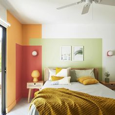 a bedroom with green, orange and yellow walls in the room that has sliding glass doors on both sides