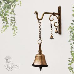 a bell hanging from the side of a wall next to a tree with green leaves