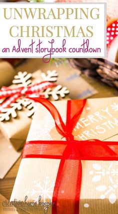 an open christmas gift box with red ribbon and snowflakes on the table next to it