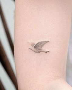 a small bird tattoo on the right arm