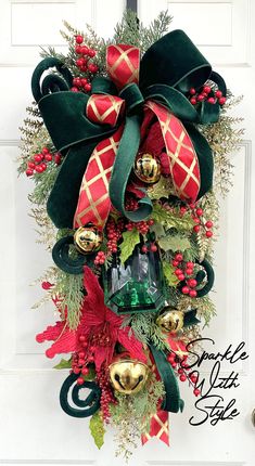 a christmas wreath hanging on the front door with bells and holly leaves, red berries, pine cones and green ribbon