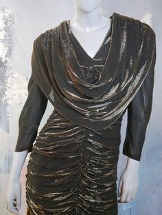 This 1980s glitter dress shimmers with gold on a black background. The stunning Austrian vintage dress has a V neckline, padded shoulders, bracelet-length sleeves, and a goddess folds yoke that drapes over the front and back to waist length The dress has a fitted waistline that gives way to a goddess pleated slimline fall to just below the hip line, where an 11-inch (27.94cm) softly ruffled panel falls to the hemline. The dress is lined in a black satin viscose fabric, and a long back zipper mak Vintage Gold Dress For Party Season, Vintage Gold Dress For Evening, Vintage Gold Dresses For Evening, Vintage Gold Evening Dress, Gold Black Dress, Silver Evening Dress, Gold And Black Dress, A Goddess, Glitter Dress