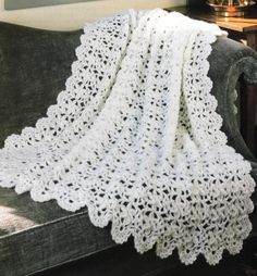 a white crocheted blanket sitting on top of a couch