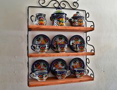 a set of four wooden shelves with plates and cups on them hanging from the wall