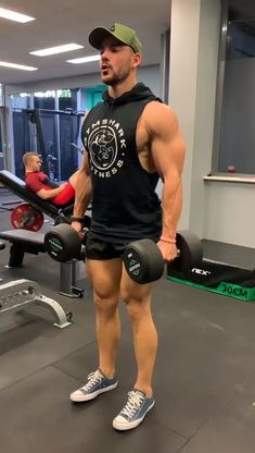 a man standing in front of a gym machine with two dumbs on his feet