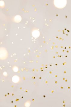 gold and white stars are flying in the air on a light gray background with boke