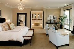 a large bedroom with white furniture and chandelier hanging from the ceiling, along with glass doors leading to another room