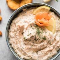 a close up of a bowl of hummus with lemon wedges