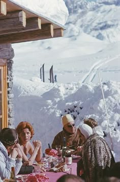 a group of people sitting at a table in the snow