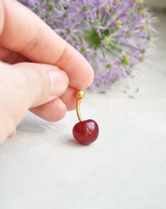 a person holding a tiny cherry in their hand