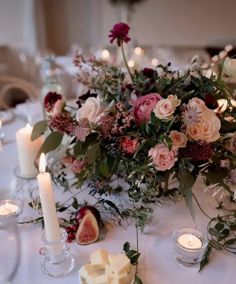 the table is set with candles, flowers and fruit for an elegant wedding breakfast or reception