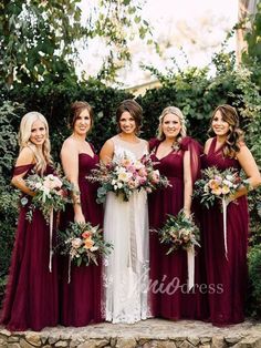 a group of women standing next to each other in front of some bushes and trees