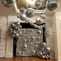 a bunch of silver balls hanging from the ceiling in a room with white walls and wood floors