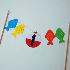 a number one sign hanging from a string with fish on it's clothes pins