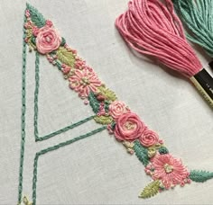 the embroidery is being worked on with scissors and thread, along with two different colored yarns