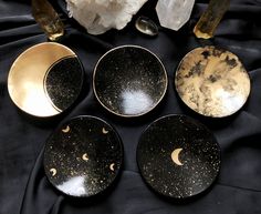 five black and gold plates with moon designs on them, next to crystal quartz crystals