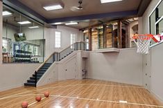 an indoor basketball court with wooden flooring and stairs leading up to the upper level