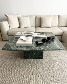 a marble coffee table sitting on top of a carpeted floor next to a couch