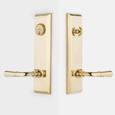 two golden door handles on a white wall