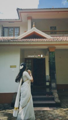 a woman in a white dress is walking out of a building