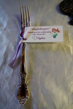 a silver fork with a purple ribbon on it and a card attached to the fork