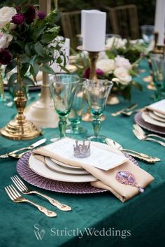 the table is set with green linens and gold place settings, including silverware