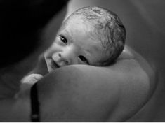 a black and white photo of a baby holding it's head in its mother's arms