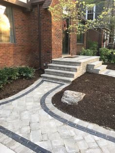 a brick house with steps leading to the front door and landscaping area on either side