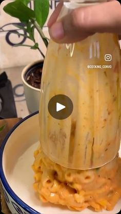 someone is pouring sauce on top of some pasta in a bowl with a green sprout