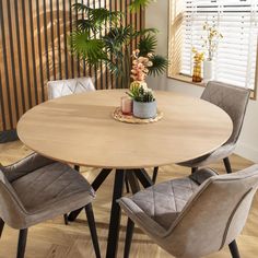 a round wooden table with four chairs around it and a potted plant on top