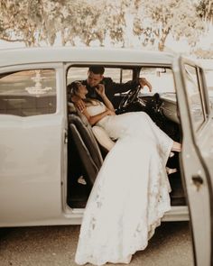 a bride and groom are sitting in the back of an old white car, kissing