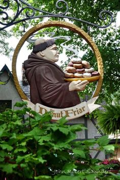 a statue of a monk holding a tray of donuts in front of a sign