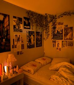 an unmade bed in a dimly lit room with posters on the wall above it