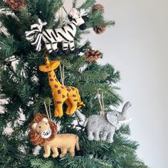 an ornament is hanging on the top of a christmas tree with animals and giraffes