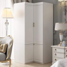 a white armoire in a bedroom next to a chair and table with a lamp on it