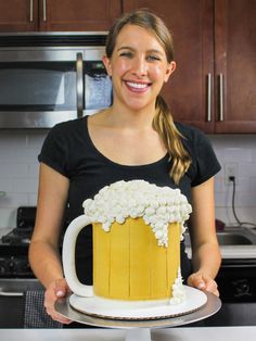 a woman is holding a cake with beer mugs on it