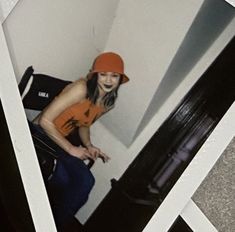 a woman in an orange hat standing next to a black suitcase