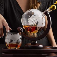 a woman is holding a wine glass and looking at the globe in front of her