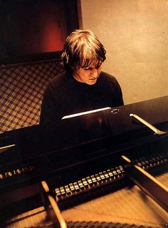 a young man sitting at a piano playing the keyboard