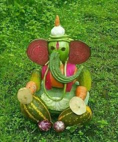 an elephant made out of vegetables sitting in the grass next to some watermelon