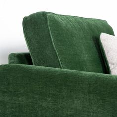 a green couch with two white pillows on it's back and the seat upholstered