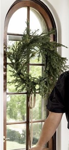 a man standing in front of a door with a wreath on the window sill