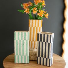 three vases with flowers in them sitting on a table