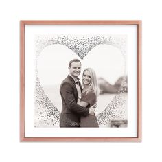 a man and woman standing next to each other in front of a heart shaped frame