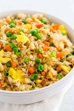 a white bowl filled with rice and veggies on top of a table cloth