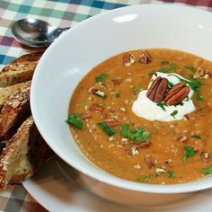 a white bowl filled with soup and topped with sour cream, pecans and parsley