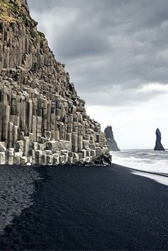 the black sand beach is lined with large rocks