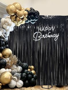 a black and gold birthday backdrop with balloons