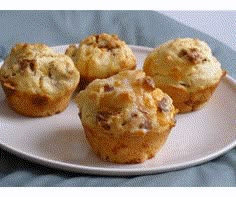 four muffins on a white plate sitting on a blue cloth covered tablecloth